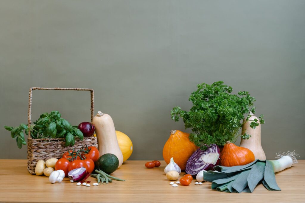 assorted fresh vegetables and a woven basket on a wooden table