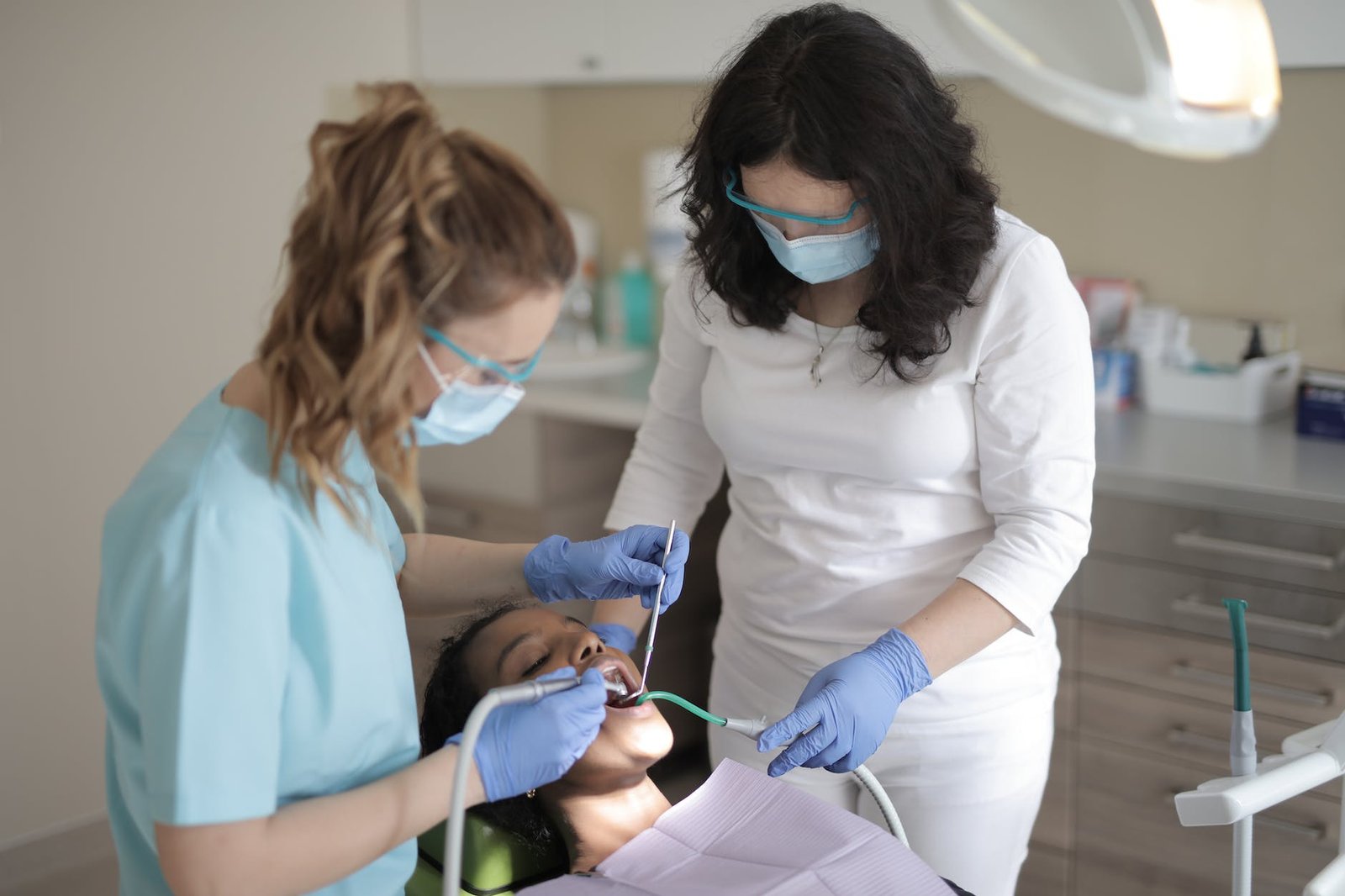 dentists treating teeth of patient in modern clinic